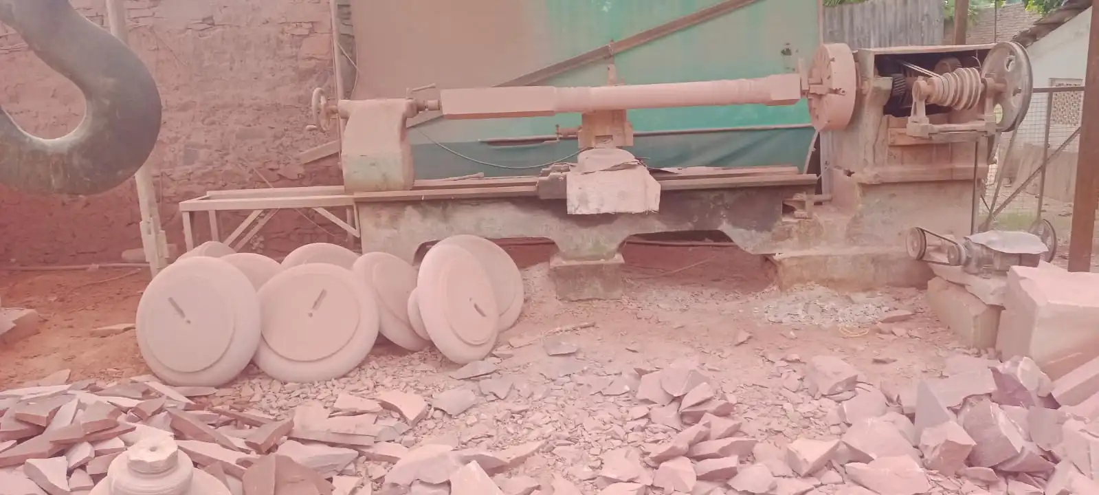 Master artisans shaping a pink sandstone pillar using traditional Kharad and turning techniques